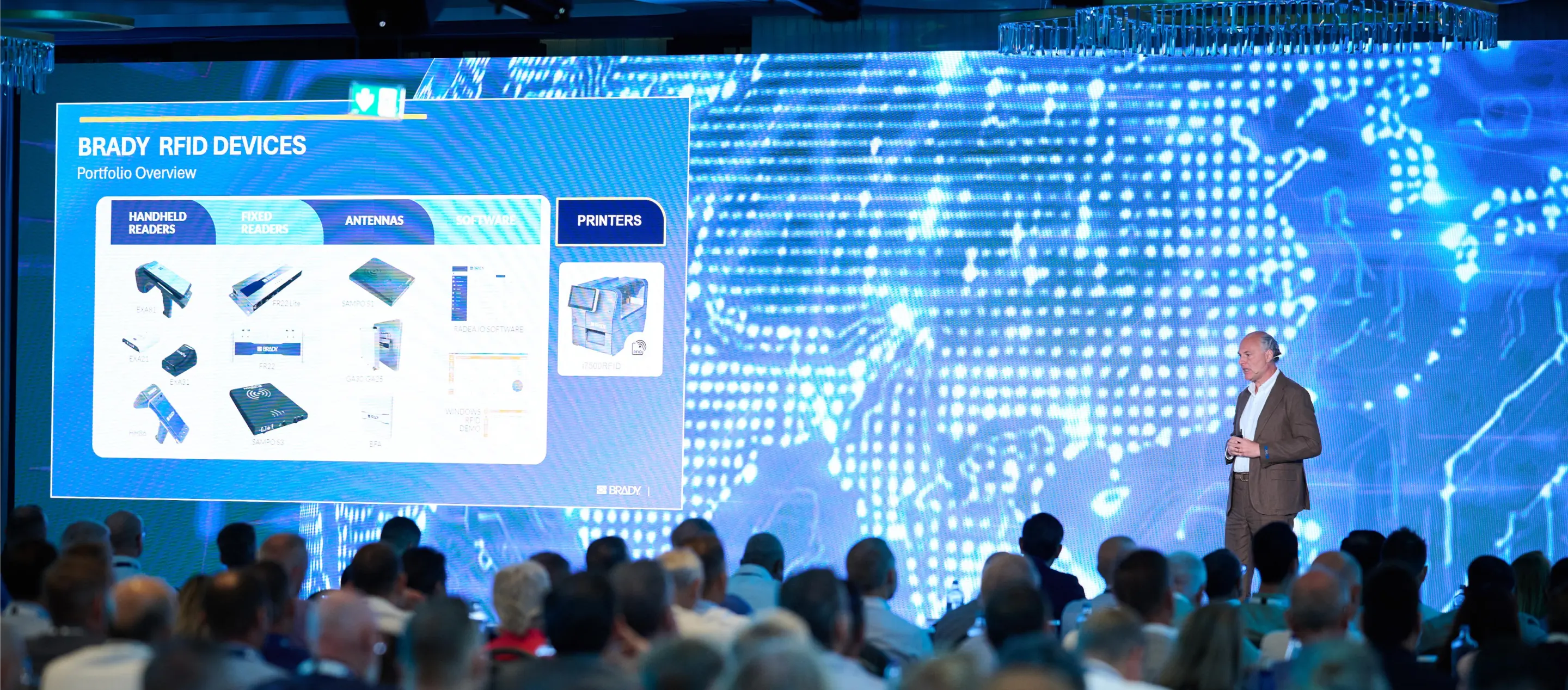 Speaker presenting traceability devices to a conference audience